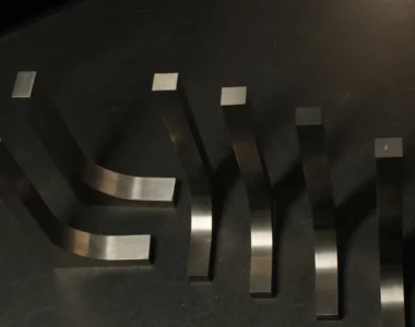 Six tungsten bucking bars of graduated sizes and curved profiles fanned out on a dark bench, showing the range a downsized tungsten set covers