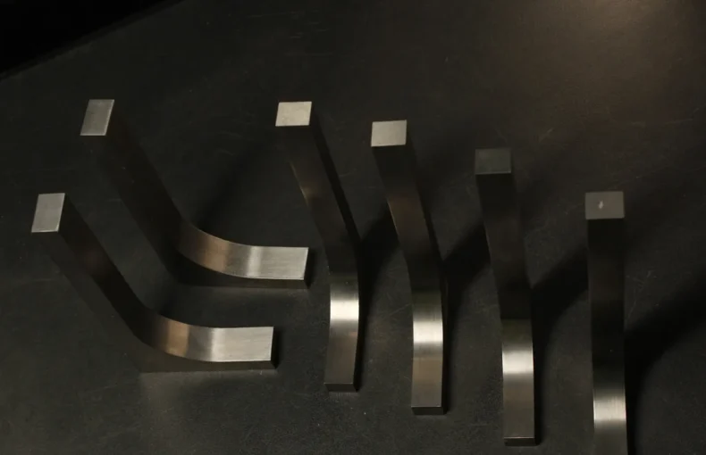 Six tungsten bucking bars of graduated sizes and curved profiles fanned out on a dark bench, showing the range a downsized tungsten set covers