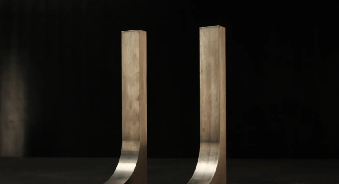Two matching tungsten hook bucking bars standing side by side on a dark bench, a small pair sized for light, controlled 3/32 inch rivet work