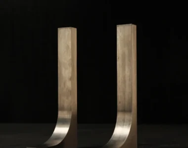 Two matching tungsten hook bucking bars standing side by side on a dark bench, a small pair sized for light, controlled 3/32 inch rivet work