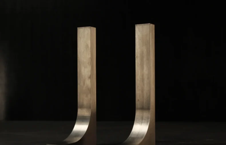 Two matching tungsten hook bucking bars standing side by side on a dark bench, a small pair sized for light, controlled 3/32 inch rivet work